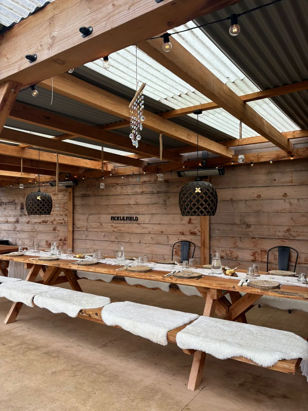 Long wooden dining table under the Fickle Field pergola
