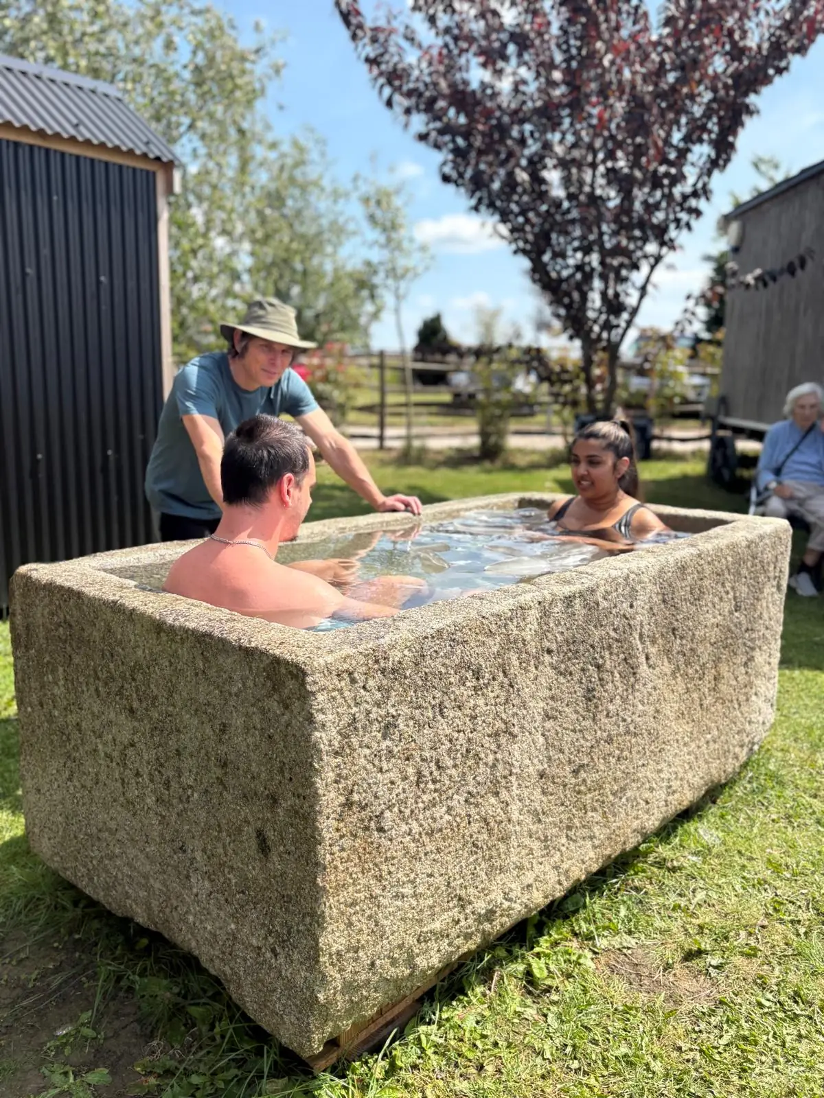 Stone cold-plunge trough with two people taking a dip